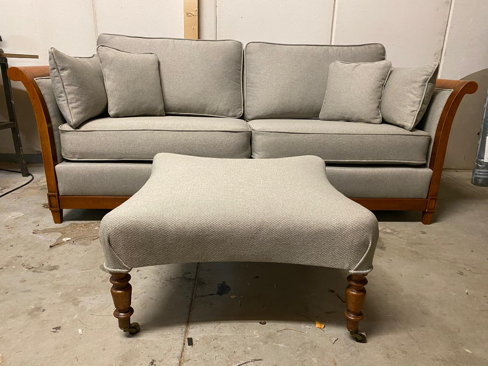 Grijze bank met houten frame en bijpassende poef